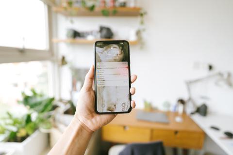 Woman holding up iPhone in work studio